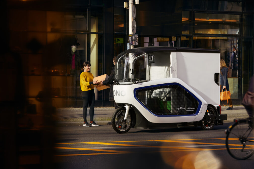Kundin empfängt ein Paket vom Fahrer des E-Cargobikes ONO.