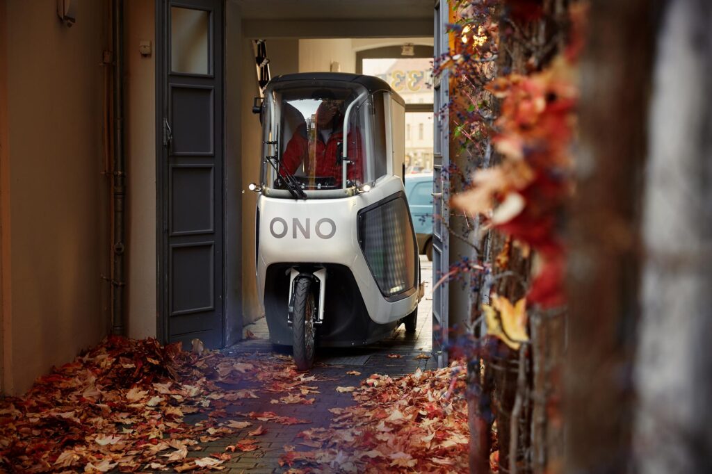 Das E-Cargobike die ONO fährt im Herbst durch einen schmalen Hauseingang in den Hinterhof.